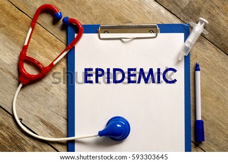 Healthcare concept. Stethoscope, syringe, pen and clipboard written with EPIDEMIC  on wooden background.