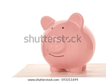 Pink ceramic piggy bank on wooden table