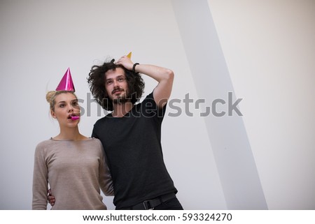 Young happy couple in party hats blowing in whistle isolated on a white background