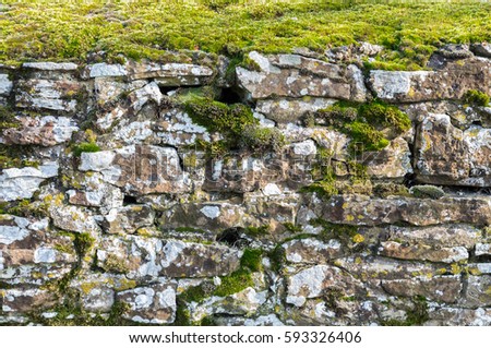 Ancient moss covered stone wall located in the village of Winchelsea, East Sussex, England.