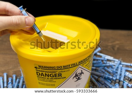 Needles being put ito a sharps bin  Royalty-Free Stock Photo #593333666