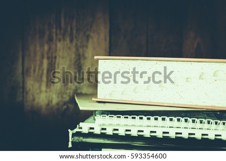 Stack of books background. many books piles. High books stack on wooden shelf background. Vintage retro picture style.