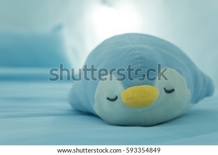 Blue penguin doll sleep on the bed.