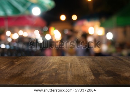 Empty wood table top and blur of  night market background/selective focus .For montage product display Royalty-Free Stock Photo #593372084