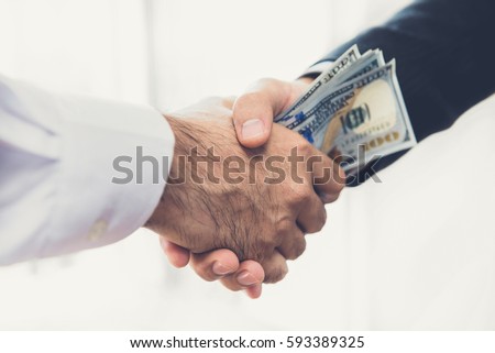 Businessmen making handshake with money in hands - bribery and corruption concepts Royalty-Free Stock Photo #593389325