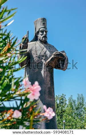 Statue of orthodox priest and flowers in Podgorica, Montenegro Royalty-Free Stock Photo #593408171