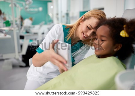 
Young female dental assistant looking in mirror girls teeth Royalty-Free Stock Photo #593429825