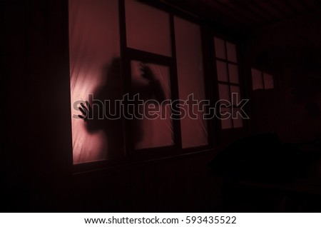 Horror concept. The silhouette of a human with sprayed arms in front of a window. at night. Azerbaijan