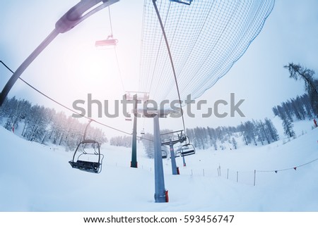 Aerial ropeway with empty chairlifts at foggy day