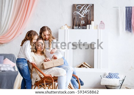 Daughters sitting in front  of the fireplace giving their mother a present