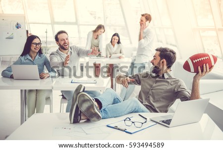 Business people are using gadgets, talking, playing with ball and smiling while working in office Royalty-Free Stock Photo #593494589