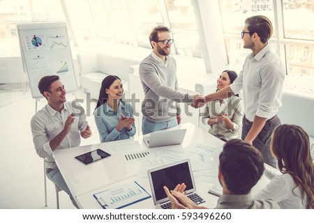 Business people at the conference. Two men are shaking hands while others are applauding Royalty-Free Stock Photo #593496260