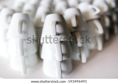 Many rows of pure white coffee cups on white table
