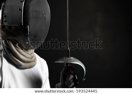 Portrait of fencer woman wearing white fencing costume practicing with the sword. Isolated on black background. Royalty-Free Stock Photo #593524445
