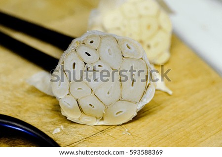 Garlic bulb sliced at the top before roasting in the oven for making roasted garlic, placed next to chopsticks. Royalty-Free Stock Photo #593588369