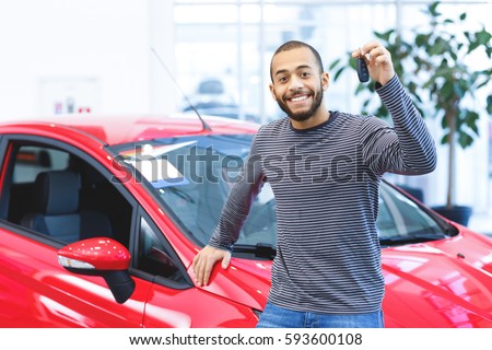 My new wheels. Attractive young African man smiling happily holding car keys to his newly bought car posing at the dealership copyspace driver owner purchase consumerism happiness buying a car concept Royalty-Free Stock Photo #593600108