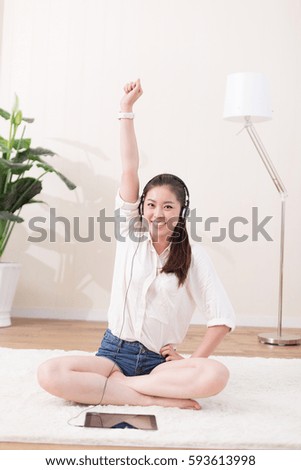 young pretty chinese woman sitting on blanket and listening music in room
