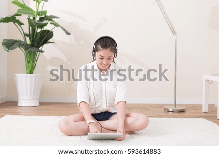 young pretty chinese woman sitting on blanket and listening music in room
