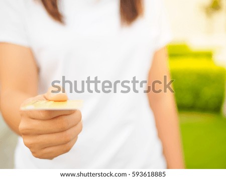 Closeup of woman's hand inserting e-card into ATM slot on the green grass background
