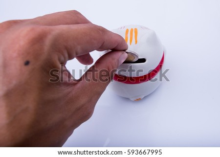 male hand putting a coin into ceramic cat bank