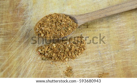 Wooden spoon of natural spice for meat on a kitchen board with scratches