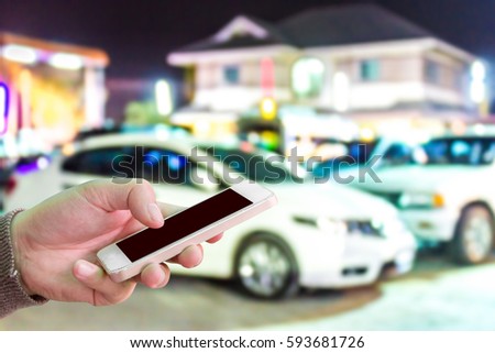 Man use mobile phone, blur image of car parked in front of house as background.