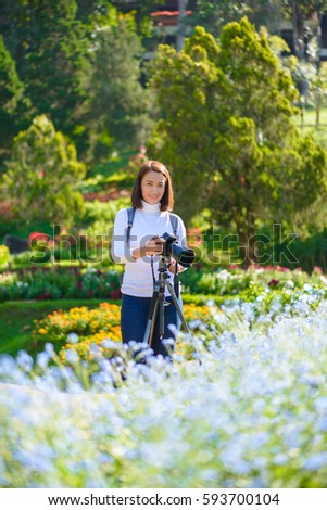 Female photographer with Tripod taking pictures of flowers in flowers garden