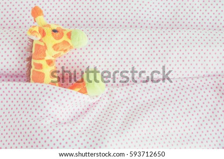 Cute giraffe lying down on the bed with a pink blanket