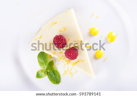 piece French lemon tart, garnished with fresh raspberries, mint and slice of lemon, top view
