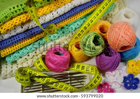 A bunch of reels with natural yarn of different colors and a stack of ready (knitted) things, inventory for hand knitting