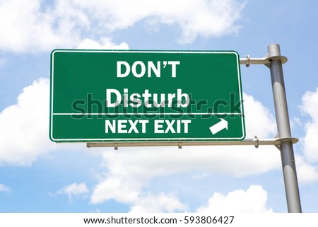 Green overhead road sign with a Don't Disturb Next Exit concept against a partly cloudy sky background. 