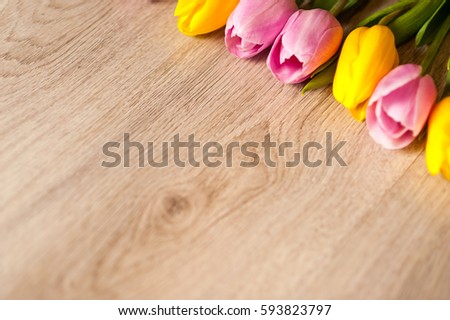 The composition of tulips of different colors on a wooden background, greeting card with free place for inscriptions on Easter or any holiday