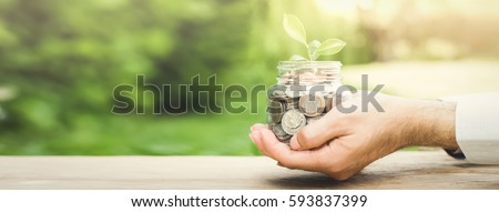 Plant growing from money (coins) in the glass jar held by a man's hands  - business and financial metaphor concept, web banner with copy space