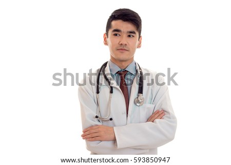 portrait of pretty young brunette male doctor in uniform with stethoscope posing and looking aside isolated on white background