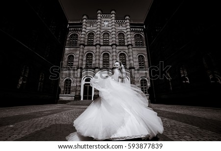 Black and white picture of stunning bride whirling on the frontyard of an old house