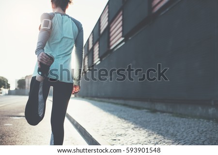 Woman athlete doing warming stretching in the city street. Tight sport clothes. Urban workout Royalty-Free Stock Photo #593901548