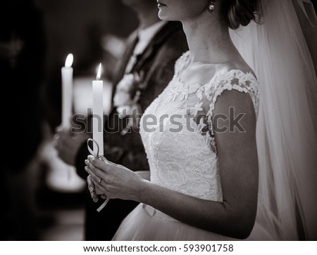 Black and white picture of wedding couple holding burning candles during the ceremony