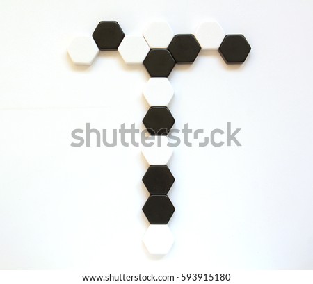 Black and white geometrical alphabet letters made of hexagonal figures laid side by side. Letter T