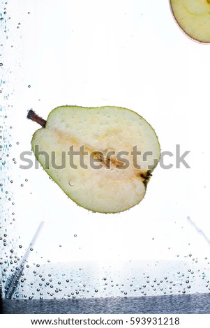Half of pear floats in aquarium with white background