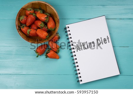 Concept image, strawberry with notebook on a blue wooden background with words Atkins Diet. Health concept. Royalty-Free Stock Photo #593957150