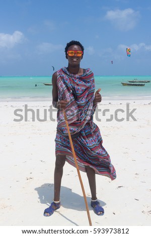 Traditonaly dressed black man with funny sunglasses on Paje beach. Maasai warrior on picture perfect tropical sandy beach on Zanzibar, Tanzania, East Africa.