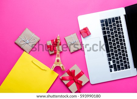 beautiful eiffel tower shaped toy, cute gifts, shopping bag and cool laptop on wonderful pink background