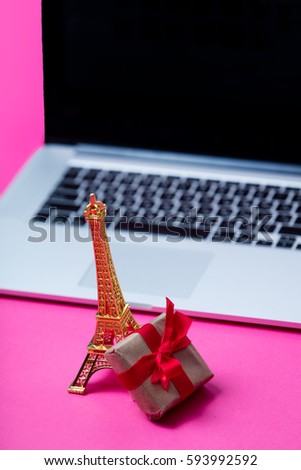 beautiful eiffel tower shaped toy, small gift and cool laptop on wonderful pink background