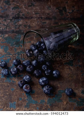 Fresh organic blueberries in the glass over the rustic wooden board. Clean eating concept. Dark Rustic Style. Top View
