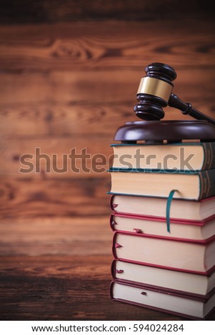 stack of law books with judge's gavel on top , studio picture on old wood background