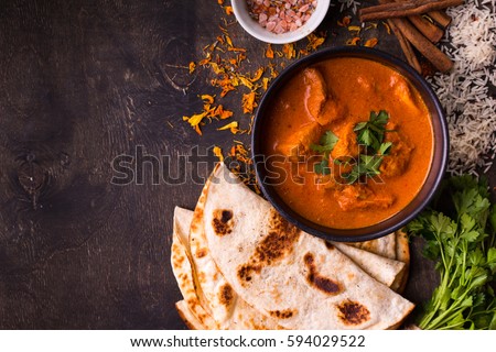 Spicy chicken tikka masala in bowl on rustic wooden background. With rice, indian naan butter bread, spices, herbs. Space for text. Traditional Indian/British dish. Top view. Indian food. Copy space Royalty-Free Stock Photo #594029522