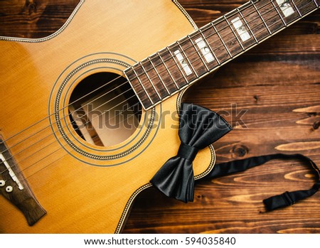 Acoustic guitar and a tie on a wooden surface