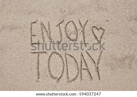 inspiring words "Enjoy today" written on the sand