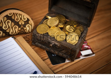 A box of coins, small purse and note book over the wood.