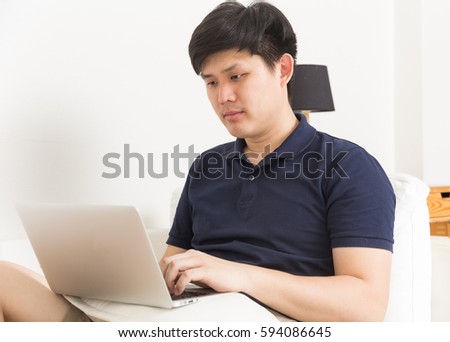 Asian Man using laptop on the couch
